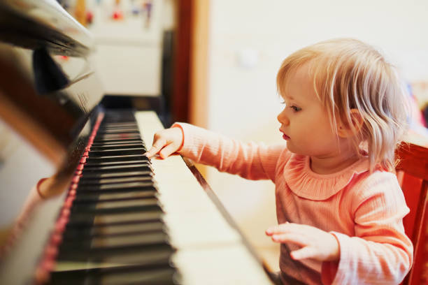 Adorable little girl playing piano. Toddler having fun while learning how to play music. Musical education for small kids
