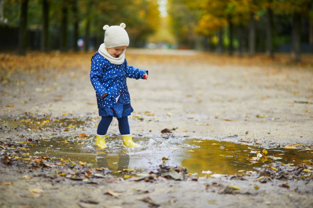 istock Child wearing yellow rain boots and jumping in puddle 1190246750
