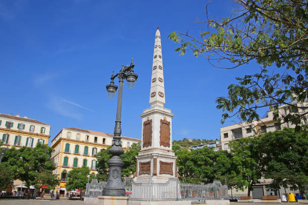 General Torrijos Monument which is obelisk shaped & situated in the downtown city centre public square; Plaza de la Merced, Malaga, Andalusia, Southern Spain.