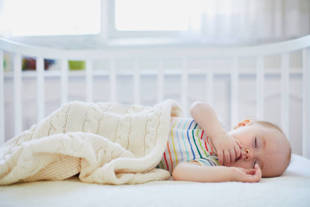 istock Baby sleeping in co-sleeper crib attached to parents' bed 1190247610