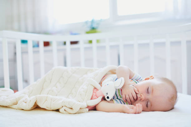 istock Baby sleeping in co-sleeper crib attached to parents' bed 1190247691