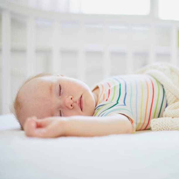 istock Baby sleeping in co-sleeper crib attached to parents' bed 1190247850
