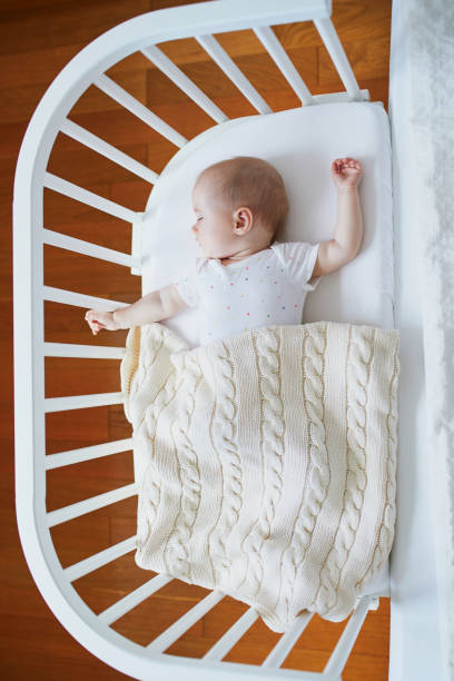 istock Baby sleeping in co-sleeper crib attached to parents' bed 1190247877