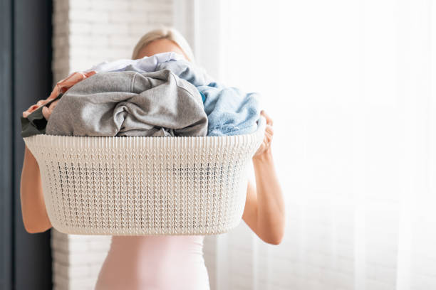 istock Young woman holding basket with laundry while standing at home 1190252635