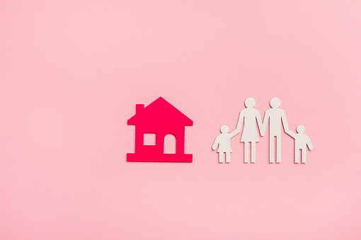 Figuras familiares con casa sobre fondo rosa