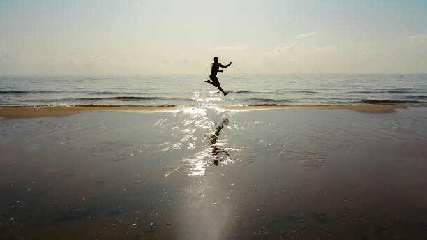 istock Man silhouette jumping on the beach 1190257306