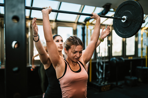 Dos mujeres jóvenes levantando pesas en el gimnasio photo