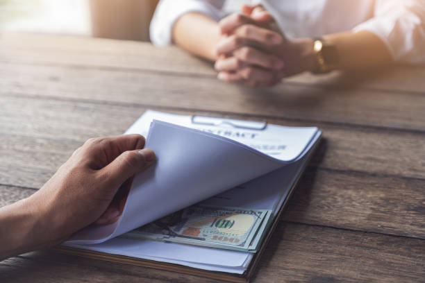 istock Compensation, fees, pay, bribery concept, Business man open contract document and look at  dollar simulation money at under document. Contracting for financial gain. 1190271130