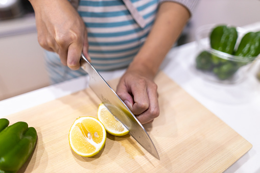 Pregnant woman cutting lemon at kitchen