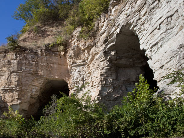 Two large partially overgrown bluff cave openings on the Great River Road along the Mississippi River in Alton Illinois USA