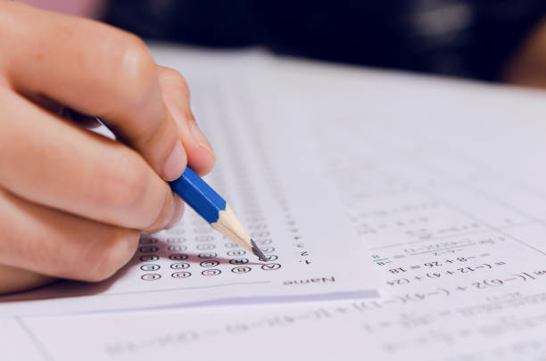 istock Students hand holding pencil writing selected choice on answer sheets and Mathematics question sheets. students testing doing examination. school exam 1190275368