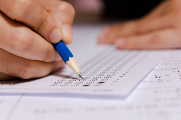istock Students hand holding pencil writing selected choice on answer sheets and Mathematics question sheets. students testing doing examination. school exam 1190275495