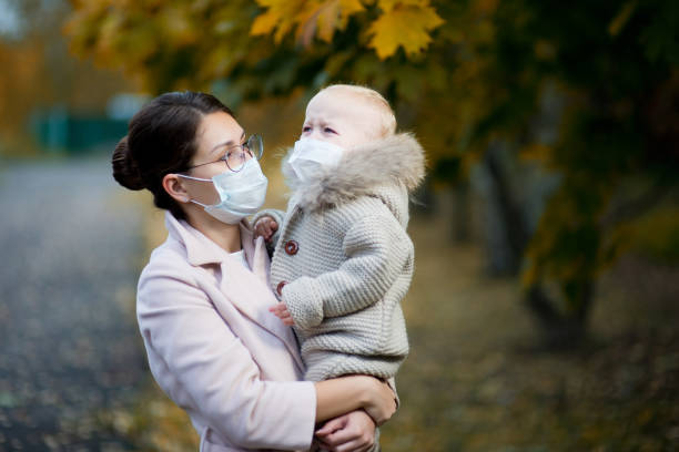 mama w medycznej masce trzyma płaczącą córkę w ramionach i patrzy na nią - 4719 zdjęcia i obrazy z banku zdjęć