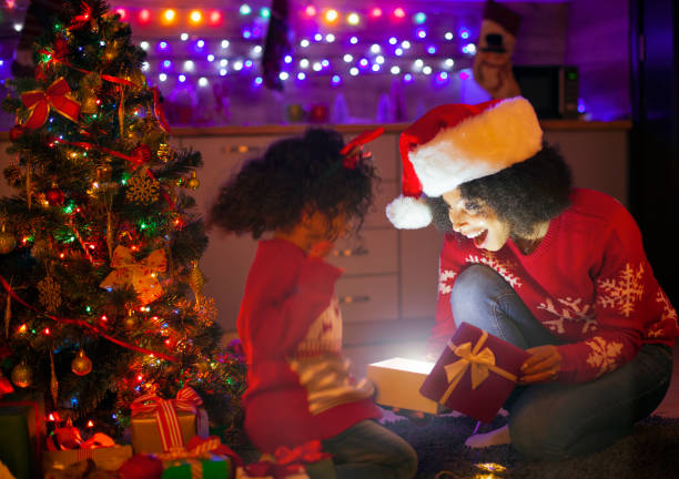 famille afro-américaine ouvrant le cadeau de cadeau de cadeau de cadeau de cadeau de cadeau de cadeau de cadeau de cadeau de cadeau de cadeau de cadeau d'éclairage - guirlande lumineuse équipement déclairage photos et images de collection