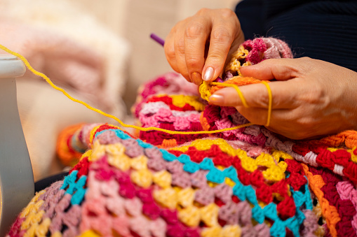 Attractive senior woman doing crocheting, making a hand-made jute basket.