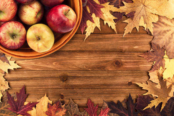 istock Apples basket and maple leaves disposed on a wooden table. 1190283244