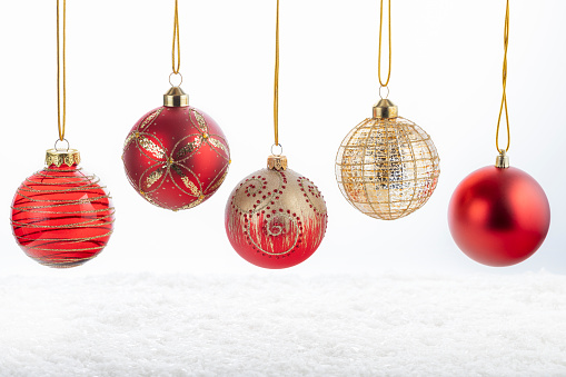 Set of five beautiful Christmas red and golden balls on white snowy background. Merry Christmas and Happy New Year concept.