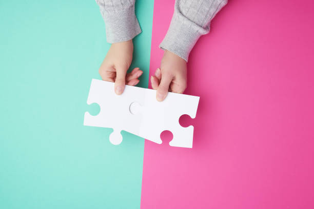 istock two empty paper white pieces of puzzles in female hands, puzzle connected 1190284715