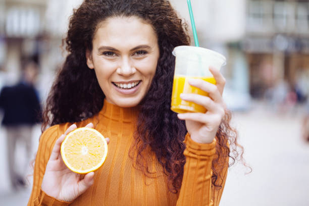 istock Beautiful young woman drinking orange juice 1190285750