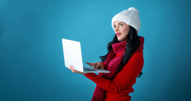istock Young woman with a laptop computer holding a Christmas gift box 1190289644