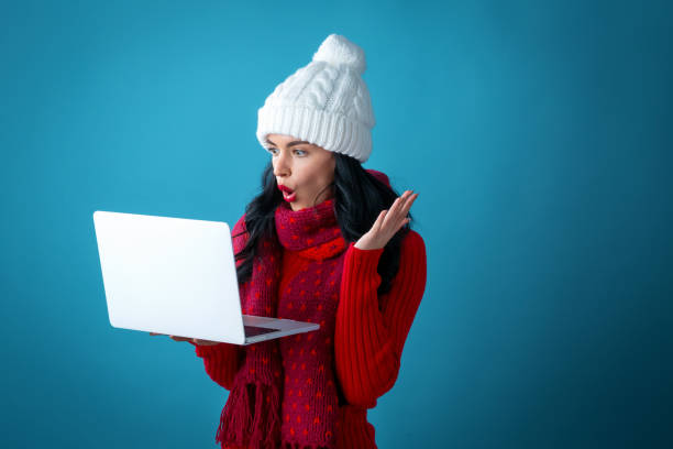 istock Young woman with a laptop computer holding a Christmas gift box 1190289648
