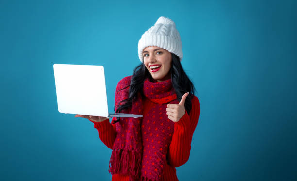 istock Young woman with a laptop computer holding a Christmas gift box 1190289649