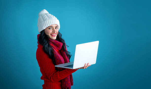 istock Young woman with a laptop computer holding a Christmas gift box 1190289662