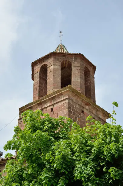 Churh tower with a windvane surrounded with verdure in the Spanish town Prades