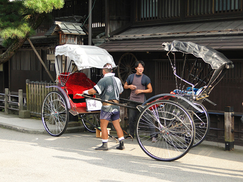 Kyoto, Japan; September 18, 2010: Rickshaw with runners Kyoto, Rickshaw,  also called jinrikisha or jinrickshaw, (from Japanese: “human-powered vehicle”), two-wheeled vehicle with a doorless, chairlike body and a collapsible hood, which holds one or two passengers and is drawn by a man between two shafts