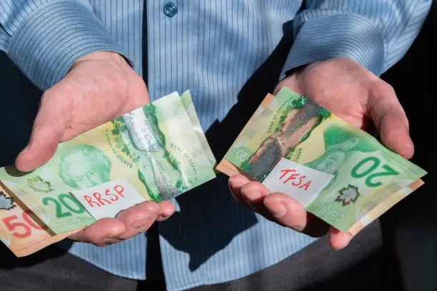 Photo of Close-up of man's hands holding Canadian cash for RRSP and TFSA investments