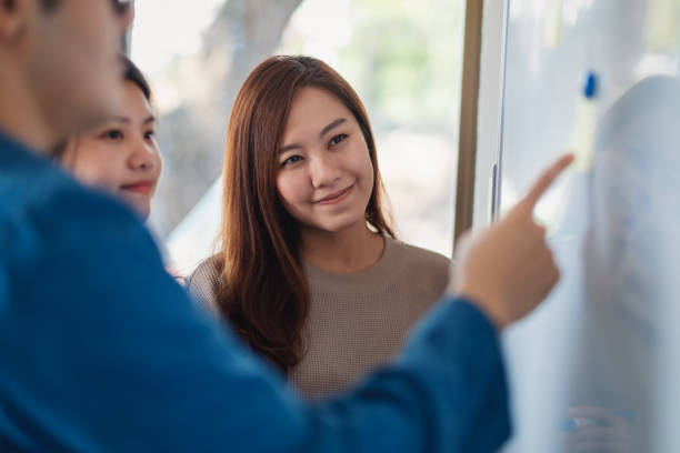 istock Business people looking, discussing and pointing finger at whiteboard 1190302236
