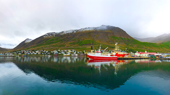 Siglufjörður, Iceland: Trawlers in a fjord harbor in late afternoon in September, with snowcapped green mountains in the background. Siglufjörður is in the Trollaskagi Peninsula in North Iceland, known for its herring industry.