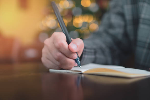 istock Woman hand writing down in small white memo notebook for take a note not to forget or to do list plan for future. 1190305295