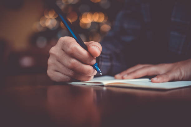 istock Woman hand writing down in small white memo notebook for take a note not to forget or to do list plan for future. 1190305320