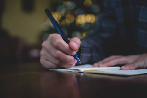 istock Woman hand writing down in small white memo notebook for take a note not to forget or to do list plan for future. 1190305321