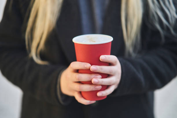istock A young girl holds a cup with coffee in her hands. 1190307749