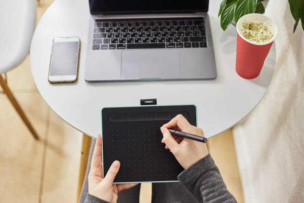 istock A young girl draws on a graphics tablet. Freelancer works in a cafe 1190310760