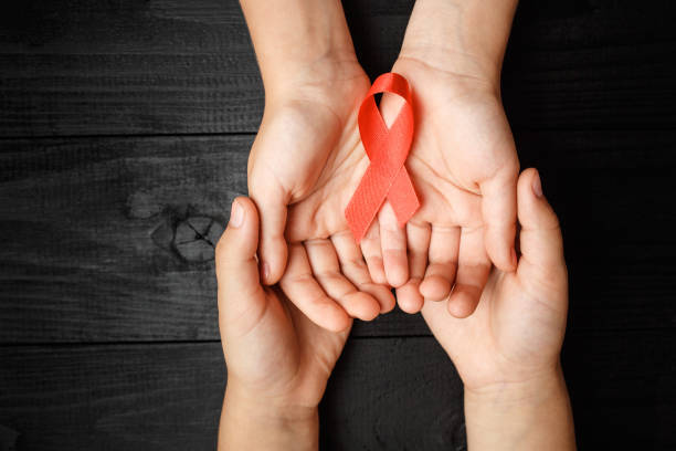 istock AID red ribbon in hand on black background 1190311915