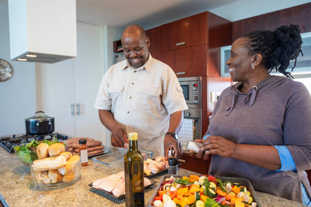 senior african couple having fun cooking together - cooking senior adult healthy lifestyle couple imagens e fotografias de stock