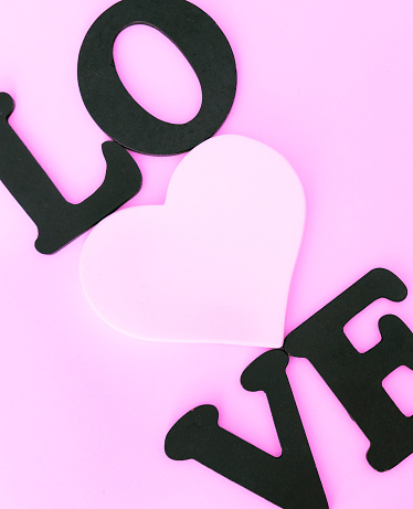 Black word Love and white heart on lilac pink background. Valentines day concept background.