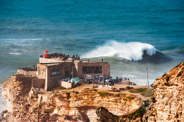 People watching big waves in Nazare, Portugal. Nazare, Portugal - November, 5, 2019: People watching big waves near the lighthouse. In this place the biggest waves in the world due to the underwater canyon nazare surf stock pictures, royalty-free photos & images
