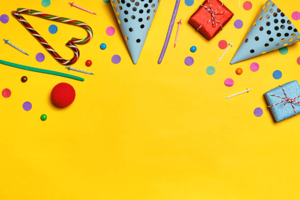 istock Birthday yellow background with party caps presents confetti candy. Copy space 1190328351
