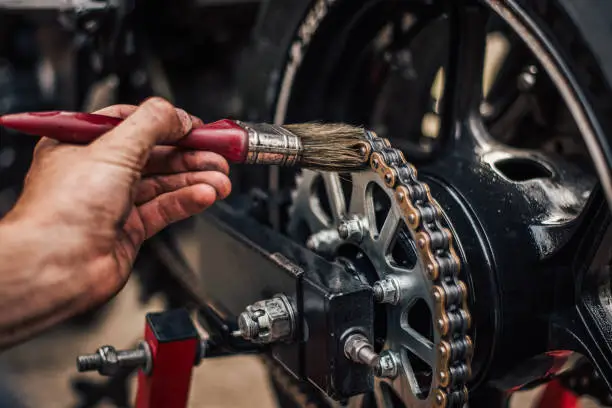 Motorcycle maintenance, lubricating chain, close-up.