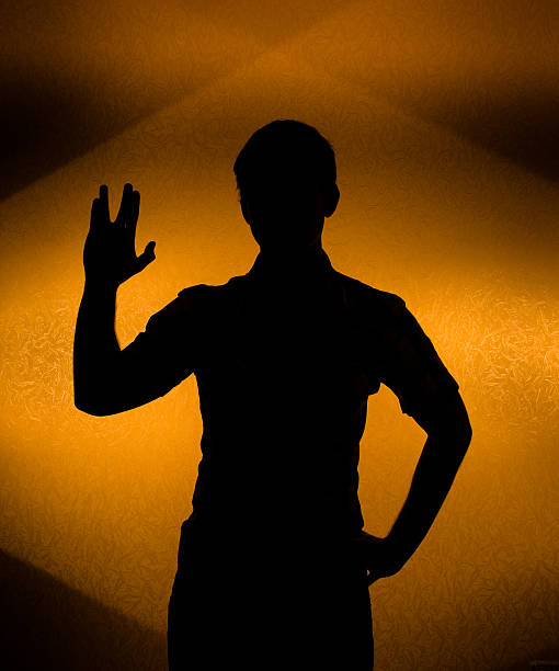 Back lit silhouette of man with raised hand Live long -  silhouette of man with raised hand vulcan salute stock pictures, royalty-free photos & images