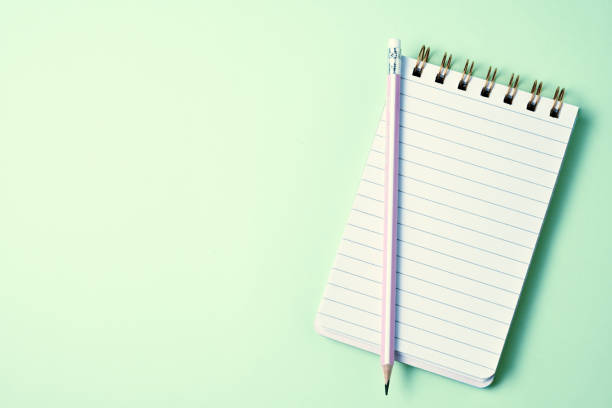 istock Top view of blank notebook with pencils on pastel green background with copy space 1190334705