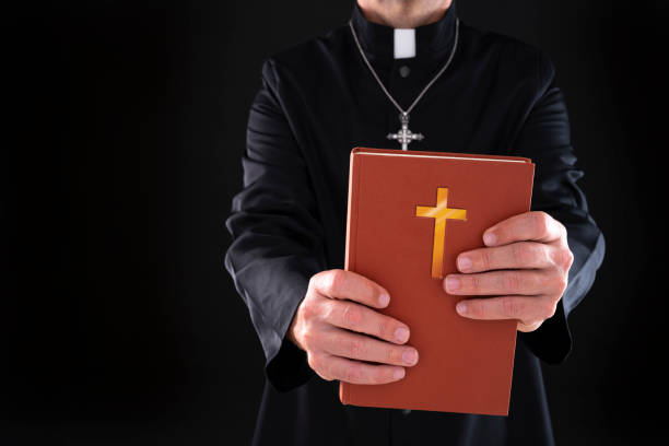 istock Priest holding hands holy bible with crucifix 1190335048