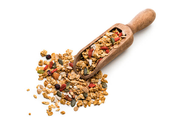 Healthy eating: Wooden serving scoop filled with granola isolated on white background. High resolution 42Mp studio digital capture taken with Sony A7rii and Sony FE 90mm f2.8 macro G OSS lens