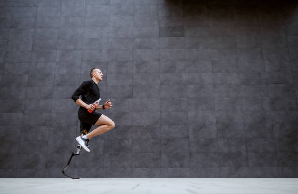 Side view of handsome fit caucasian sportsman with artificial leg running outside. Side view of handsome fit caucasian sportsman with artificial leg running outside. prosthetic equipment photos stock pictures, royalty-free photos & images