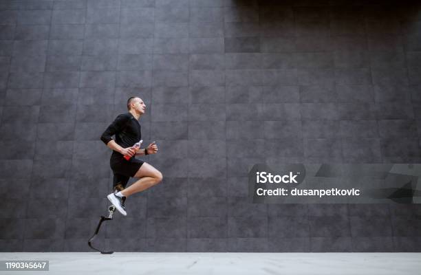 Side View Of Handsome Fit Caucasian Sportsman With Artificial Leg Running Outside Stock Photo - Download Image Now