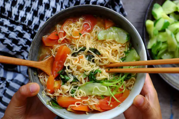 Top view Vietnamese food, vegan instant noodles soup with tomato, spice, vegetables, cheap and quick meal for breakfast
